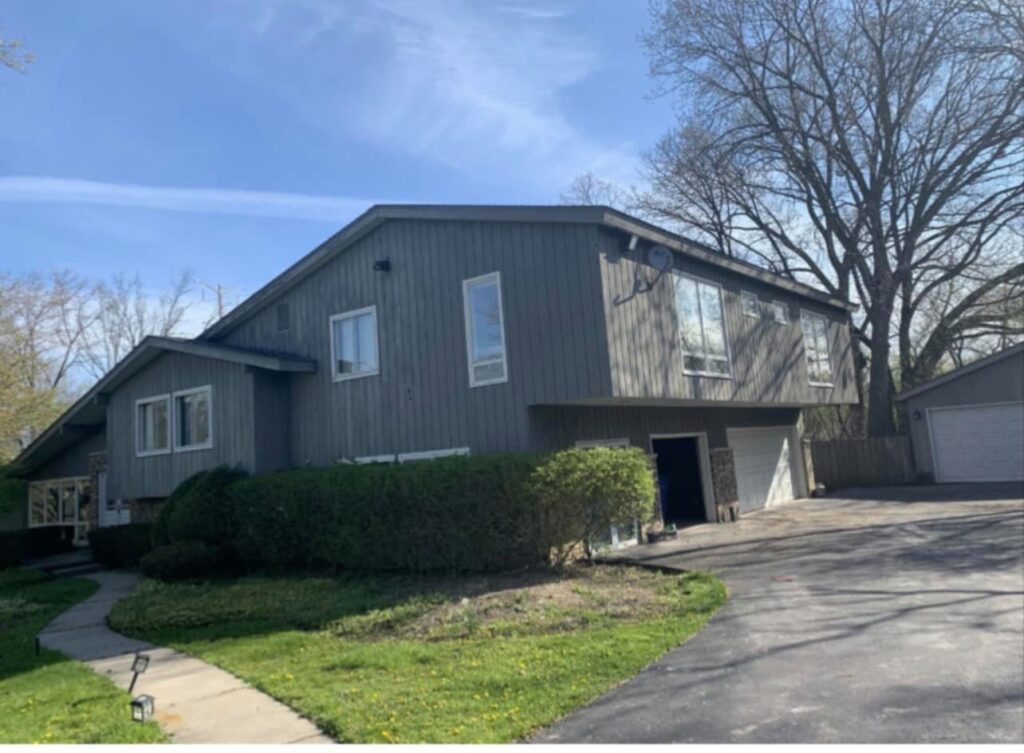 Home exterior before roof replacement and siding renovation - worn roof and outdated gutters